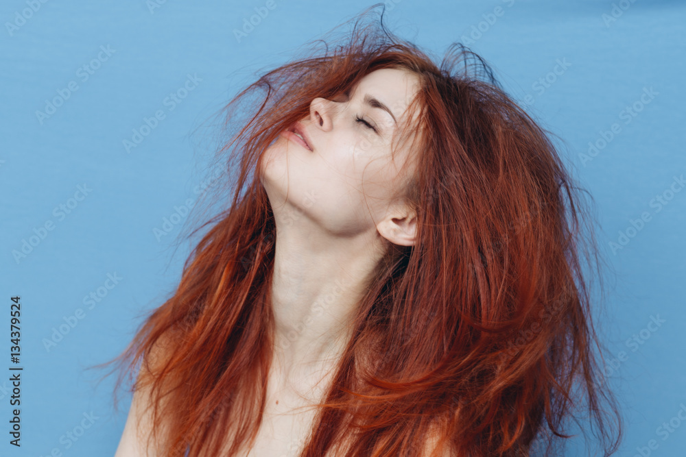 woman with tangled hair raised her head up against a blue background woman with tangled hair raised her head up against a blue background