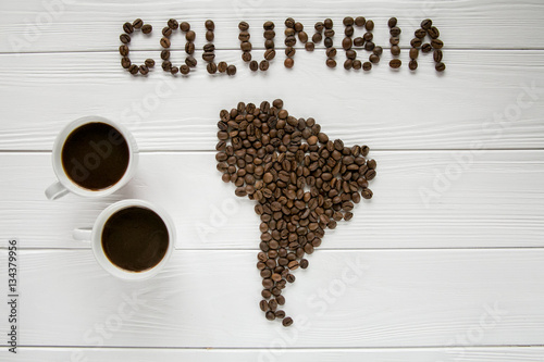 Map of the Columbia made of roasted coffee beans laying on white wooden textured background with two coffee cups. Space for text