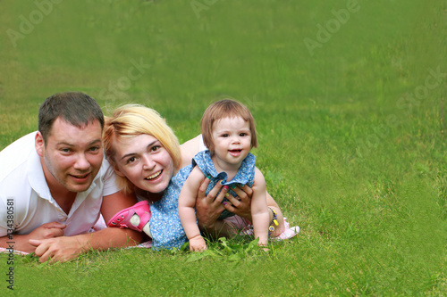 Portrait of happy family outdoors sitting on the green grass in