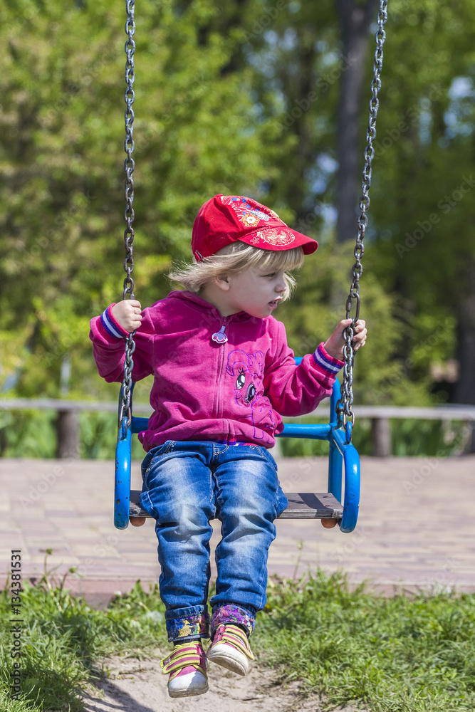 Cute little girl on a swing. Smiling child playing outdoors. Cute little girl on a swing. Smiling child playing outdoors.