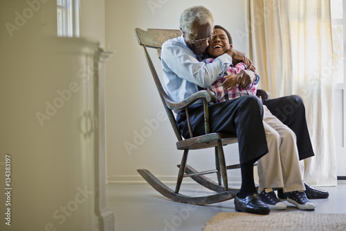 Senior man sitting in a rocking chair with his grandson.