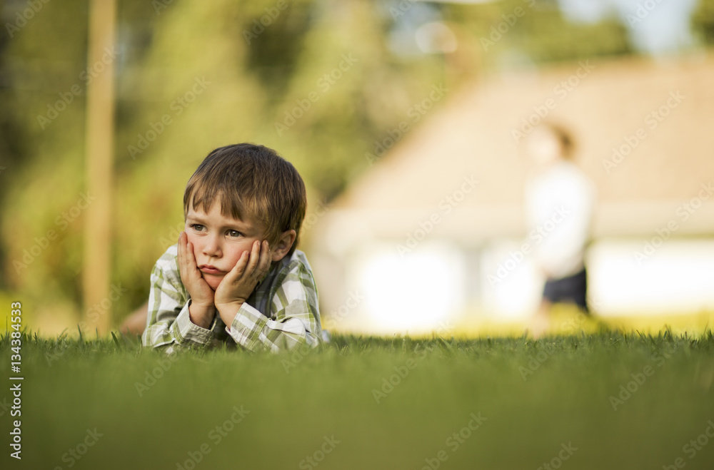Thoughtful boy lying on the grass Thoughtful boy lying on the grass