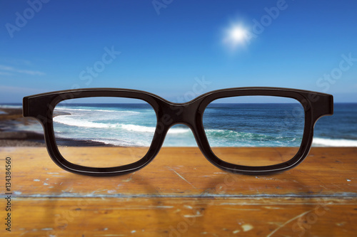 schwarze Brille liegt auf einem Tisch mit Meerblick 