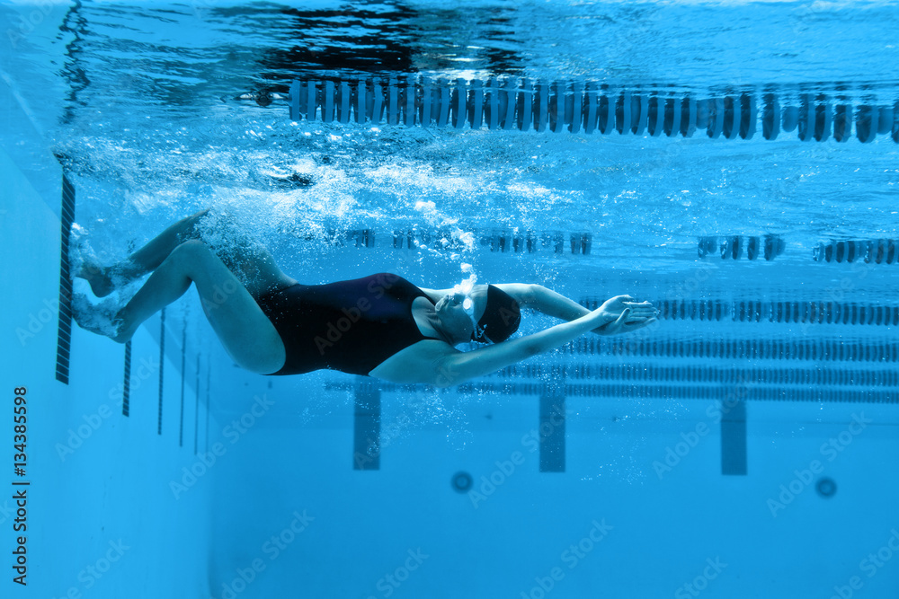 Female swimmer pushing off from the swimming pool wall. Stock Photo