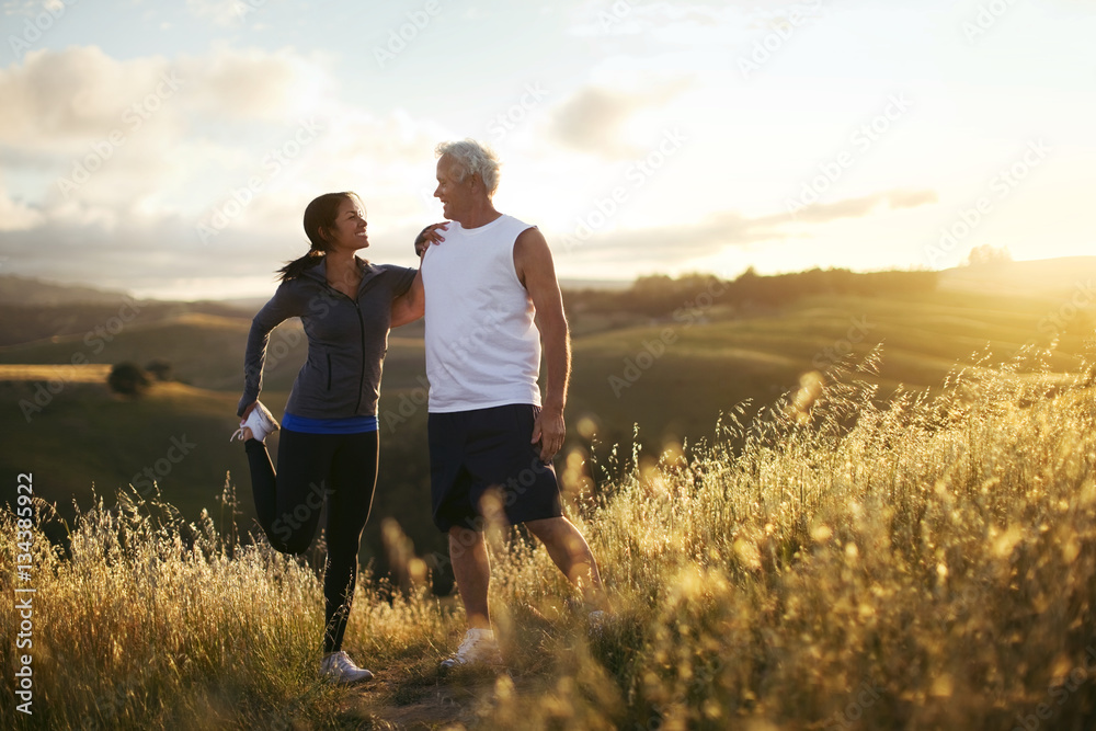 Man and woman stretching while exercising in a rural landscape. Man and woman stretching while exercising in a rural landscape.