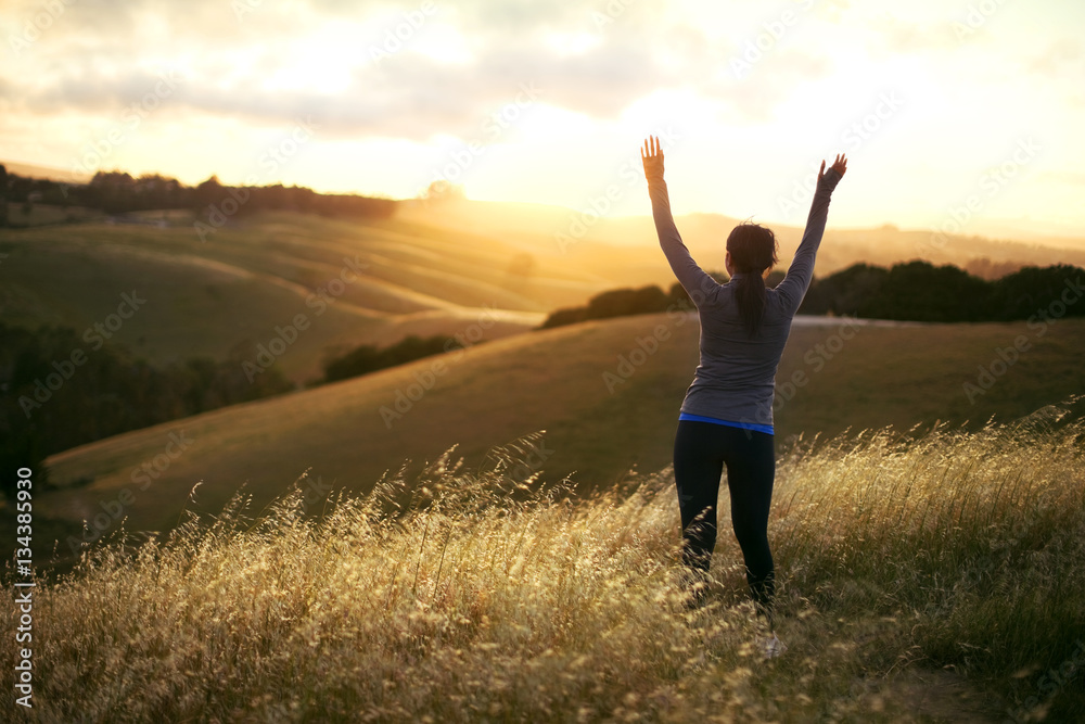 Woman raising her arms over a rural landscape while exercising. Woman raising her arms over a rural landscape while exercising.