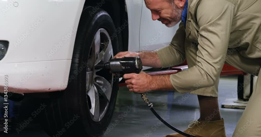 Mechanic fixing a car wheel with pneumatic wrench in garage 4k Mechanic fixing a car wheel with pneumatic wrench in garage 4k