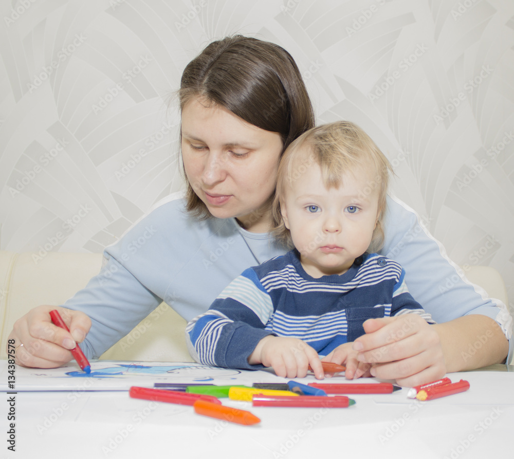 Mother and son are drawing together with pencils at table Mother and son are drawing together with pencils at table