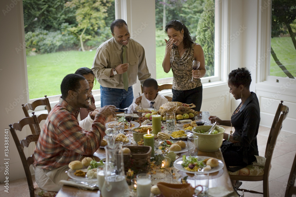Smiling family gathered around a dining table. Smiling family gathered around a dining table.