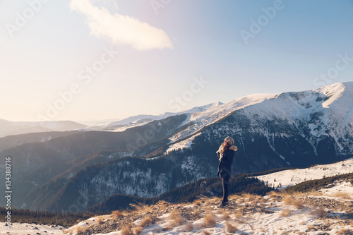 Winter view of a young woman admiring mountain landscape. Selective focus. Film filter