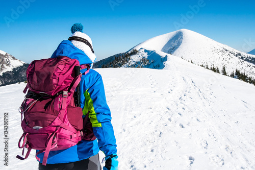 Woman on mountain top, self confident woman in winter mountains, symbol winter experience, background hiker in mountains