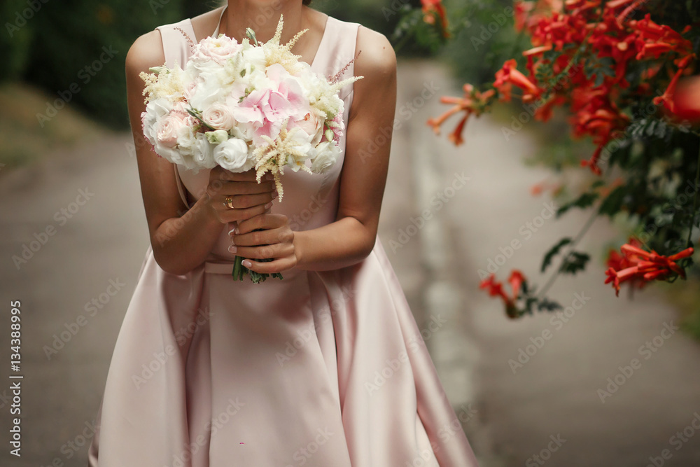 bride holding wedding bouquet of pink roses and white flowers in