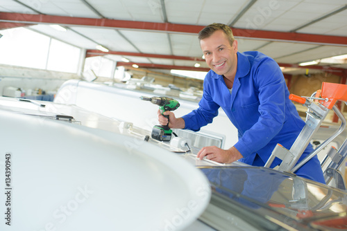 Mechanic working on roof of vehicle