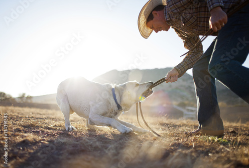 Smiling rancher playing with dog outdoors