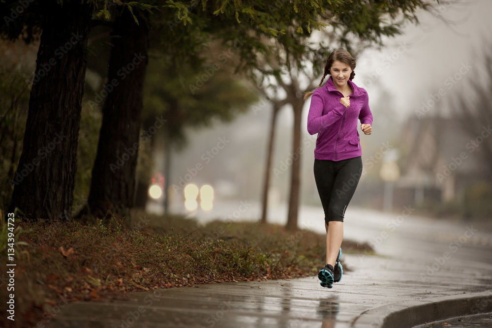 Young woman jogging on a residential street. Young woman jogging on a residential street.