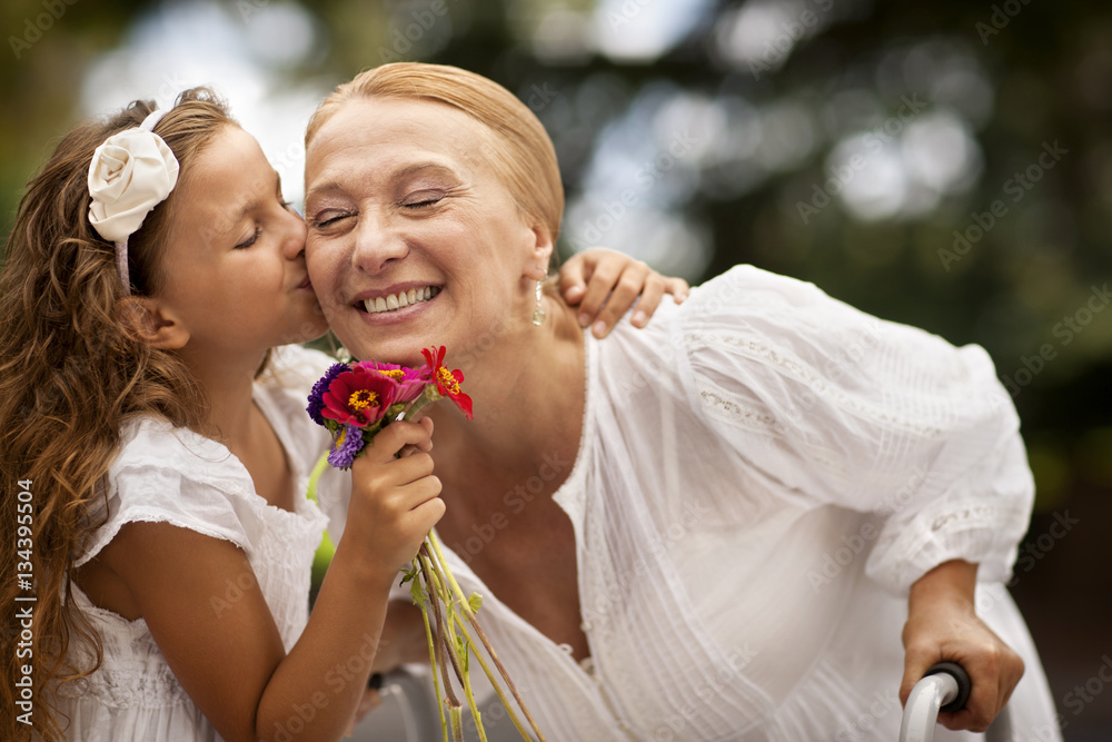 Young girl kissing her grandmother's cheek. Young girl kissing her grandmother's cheek.