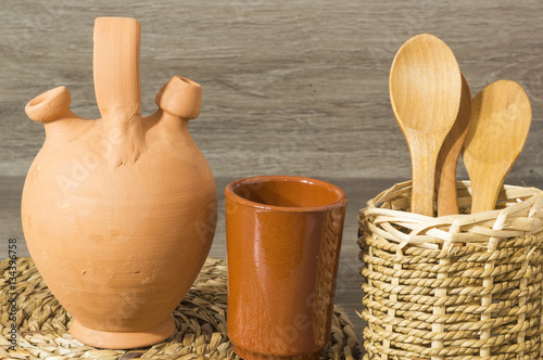 Un botijo de barro, un vaso de barro, cucharas de madera photo