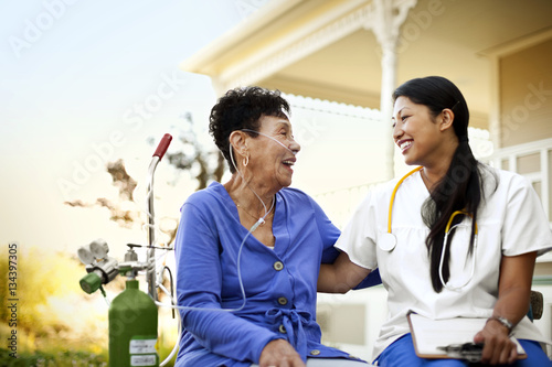 Female nurse sitting with the patient in garden with an oxygen tank photo