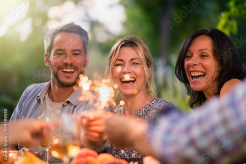 A group of friends having fun outdoors  they hold spark sticks