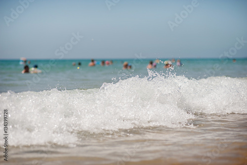 waves on the beach. silhouettes of people bathing in the background. © nfbiruza