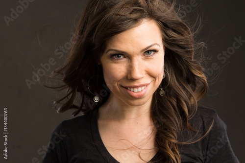 Young caucasian woman with brown hair and a black top smiles at the viewer photo