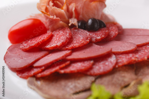 thin slices of sausage and meat on a plate white background