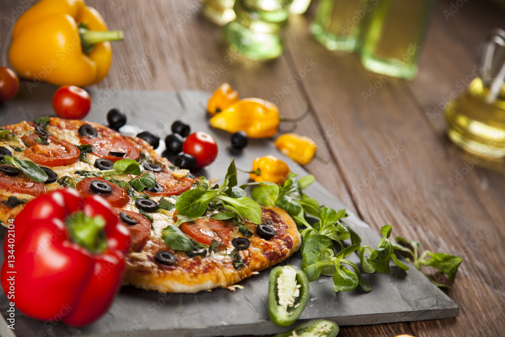 Tasty pizza, tomatoes and others ingredients on a wooden backgro Tasty pizza, tomatoes and others ingredients on a wooden backgro