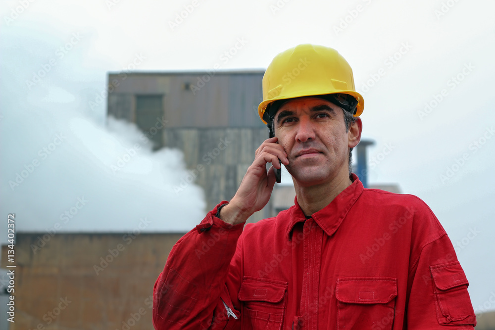 Worker Using Smart Phone With Factory in the Background Worker Using Smart Phone With Factory in the Background