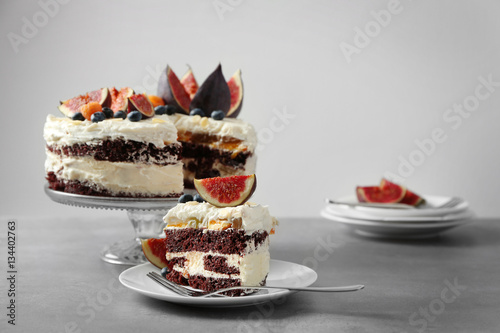 Delicious creamy cake with figs and berries on light grey background