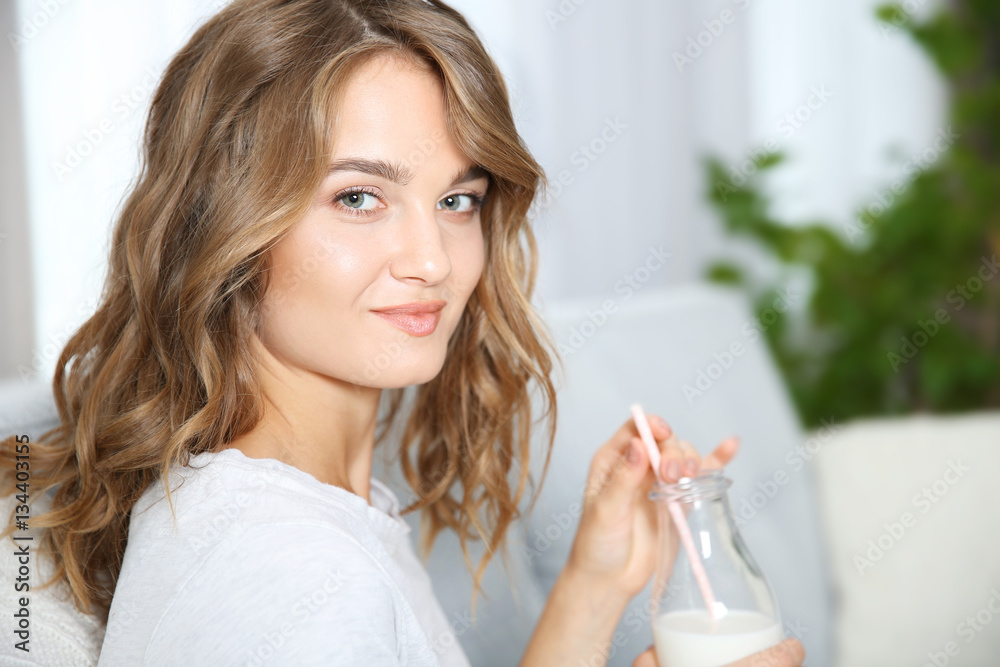 Young woman sitting on sofa with bottle of milk Young woman sitting on sofa with bottle of milk