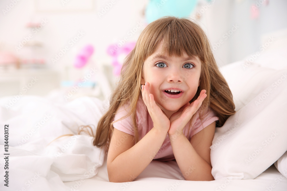 Cute little girl lying in bed at home