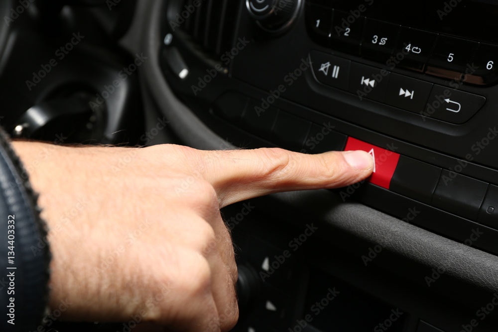 Male hand pressing emergency warning button on car console, closeup