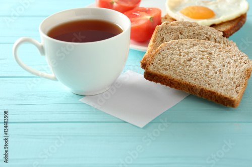 Cup of tea with tasty breakfast on wooden background