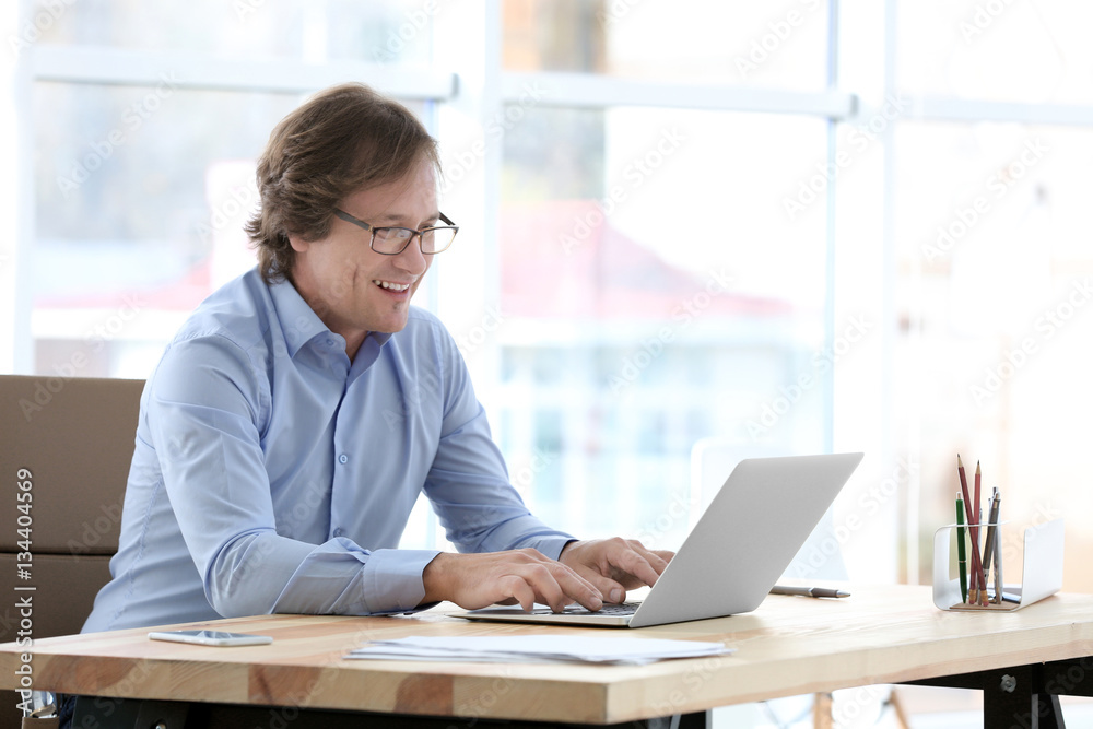 Mature man working with laptop in office Mature man working with laptop in office