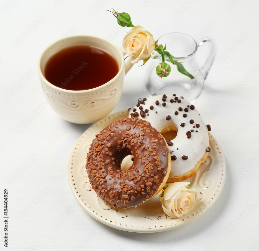 Plate with delicious donuts, cup of coffee and flower on white background Plate with delicious donuts, cup of coffee and flower on white background