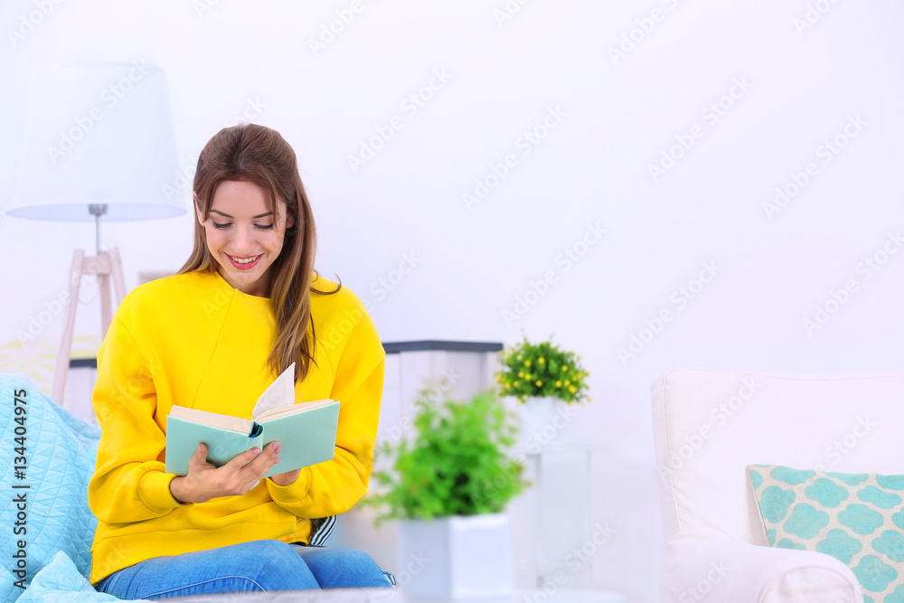 Young woman reading interesting book on sofa at home Young woman reading interesting book on sofa at home