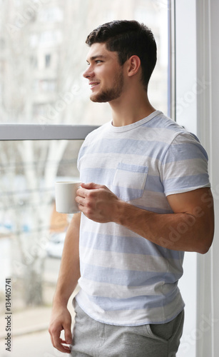 Handsome young man drinking coffee at home