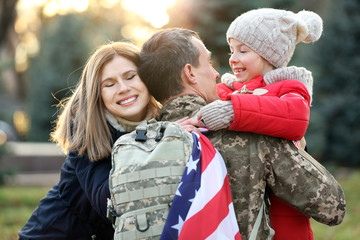 USA soldier hugging his family outdoors