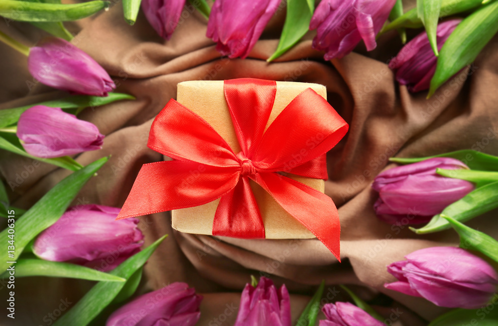 Gift box with tulips on tablecloth background Gift box with tulips on tablecloth background