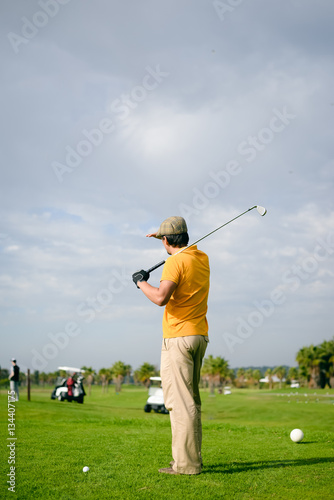 Business man holding golf club playing on grass field background. Active male outdoors