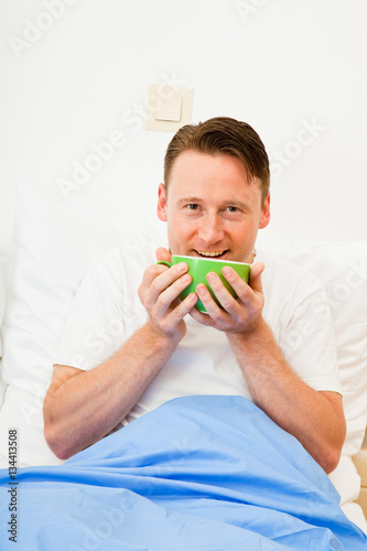 Young Man Having Coffee In Bed