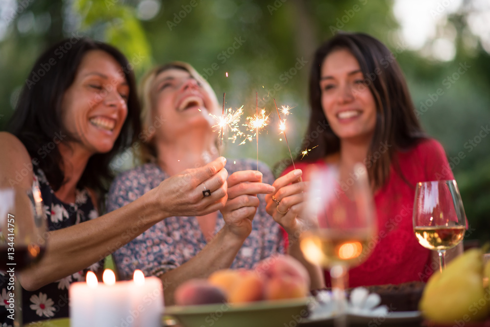 Three beautiful women having fun while they hold spark sticks