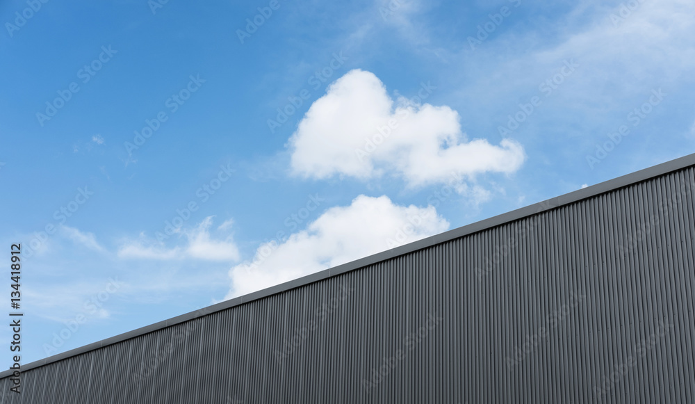 Corrugated factory industry wall on blue sky with clouds 