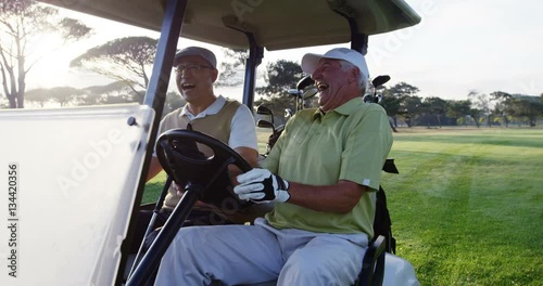 Two golfers laughing together in their golf buggy at golf course