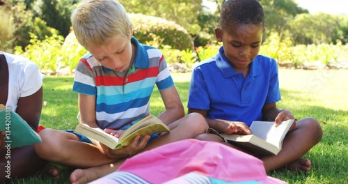 Group of smiling kids reading books in park on a sunny day 4k