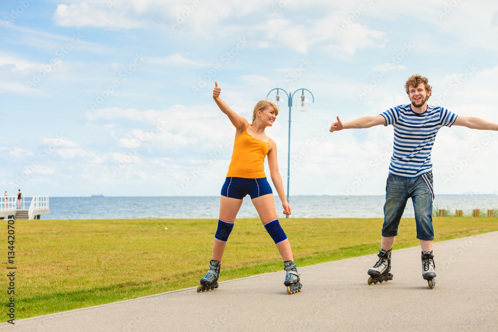 Obraz premium Young couple on roller skates riding outdoors