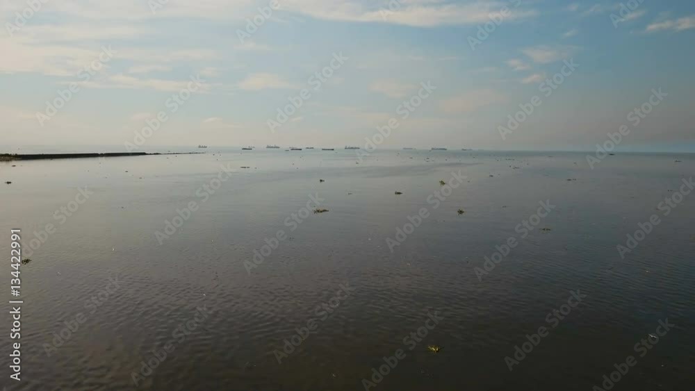 Aerial view Cargo ships in the Bay of Manila. Large container ship in the sea. Flying over the water surface of the sea with ships, blue sky and clouds. 4K video. Aerial footage. Philippines, Manila. Aerial view Cargo ships in the Bay of Manila. Large container ship in the sea. Flying over the water surface of the sea with ships, blue sky and clouds. 4K video. Aerial footage. Philippines, Manila.