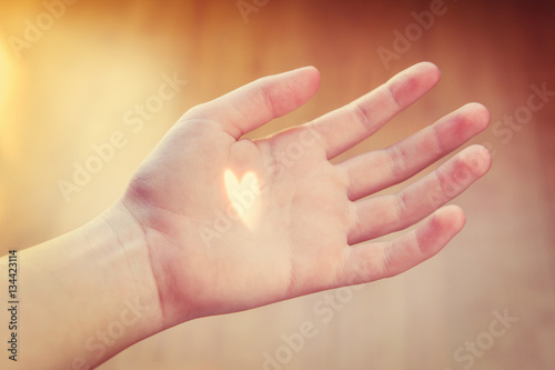 Heart shaped ray of light shining on an open hand. Shallow focus