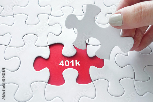 Hand placing  jigsaw puzzle with 401k text photo