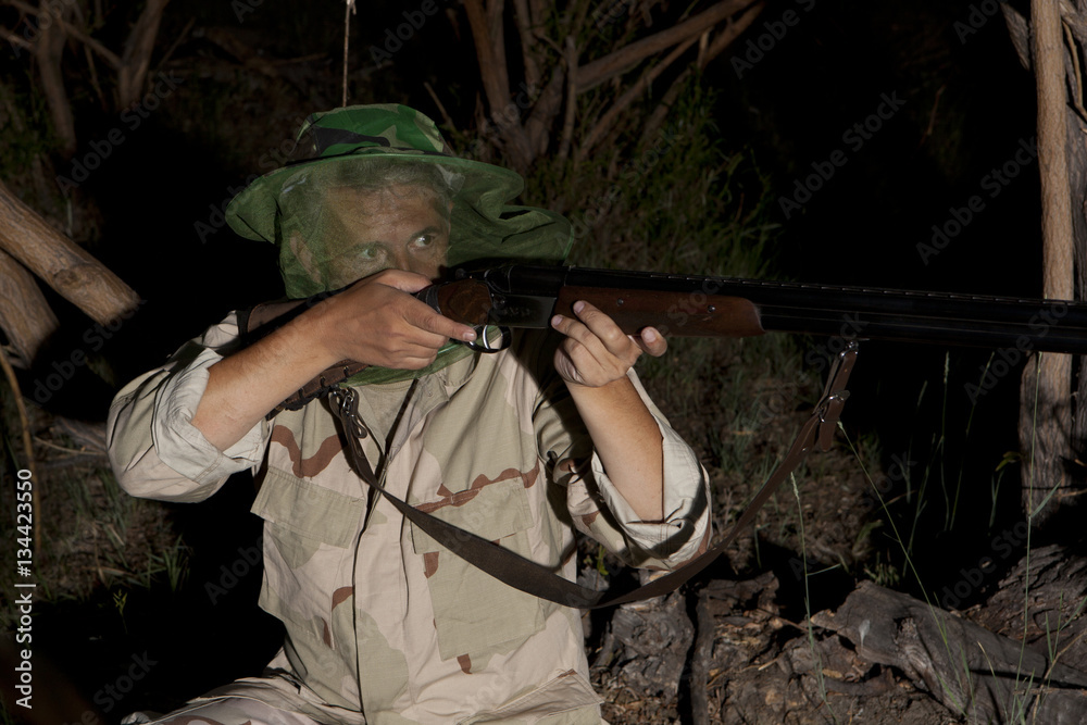 Man in mosquito net ready to hunt with hunting rifle